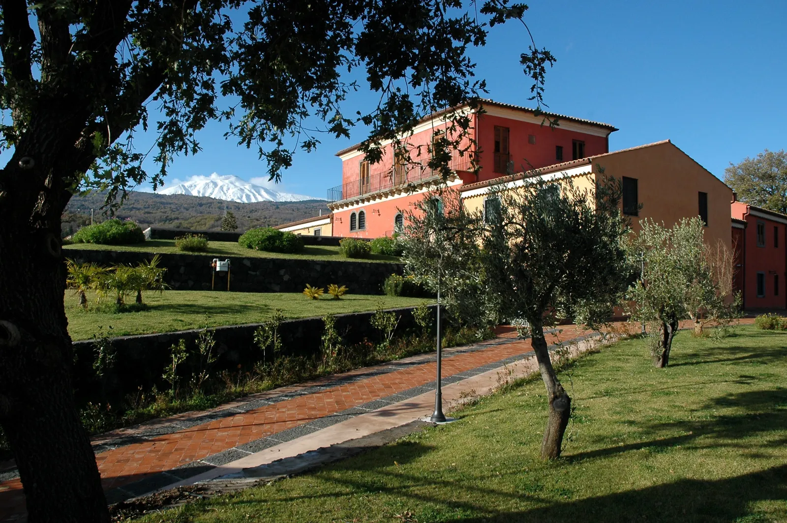 A red-washed farmhouse estate below the snow-capped cone of Etna