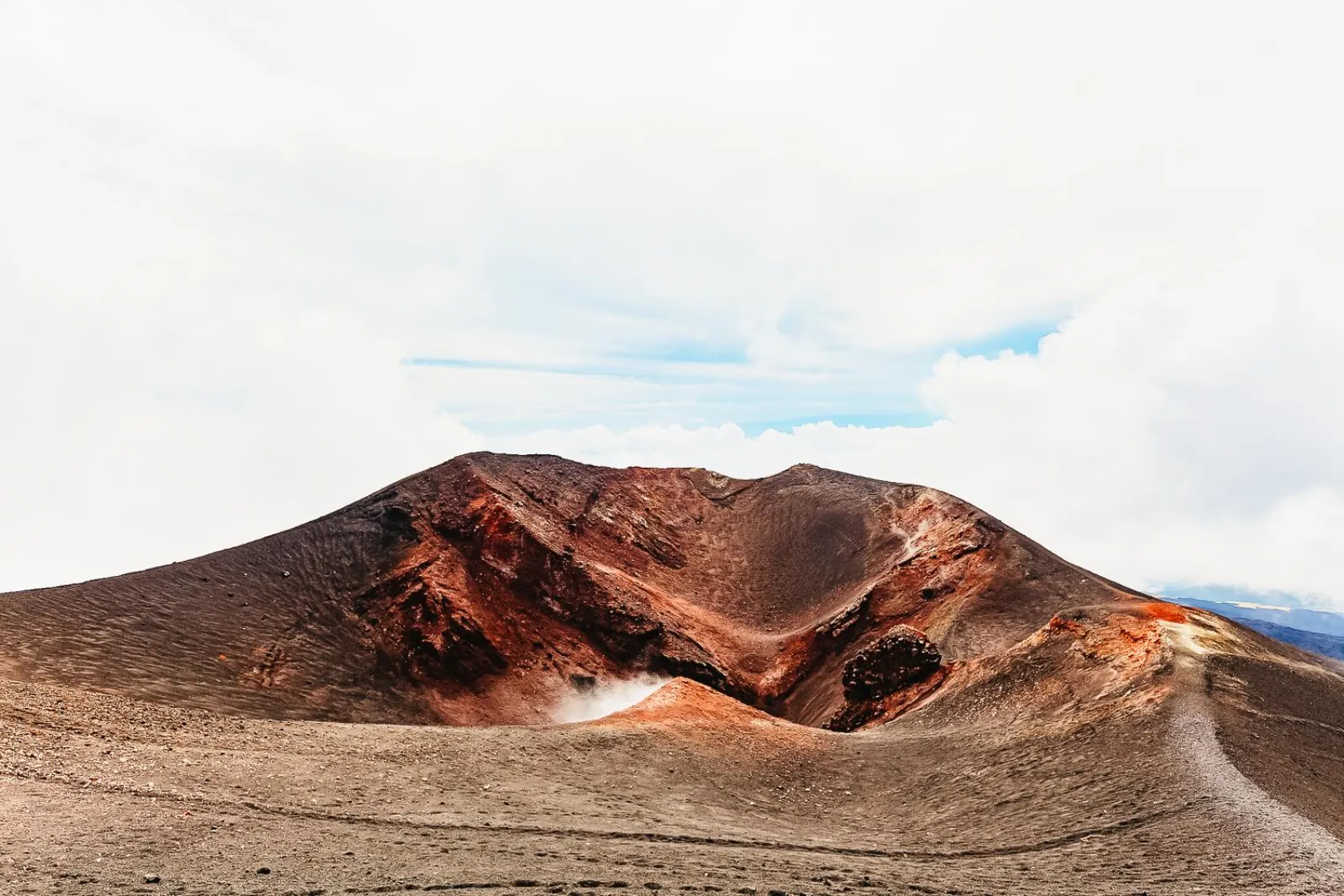A crater rim on the upper mountain, its scree stained red by oxidised ash
