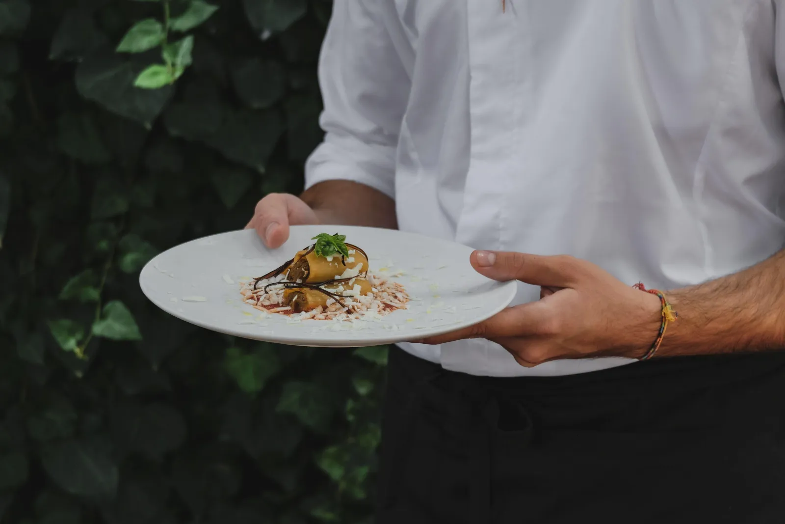 A waiter carrying out a plated pasta course to the shared table