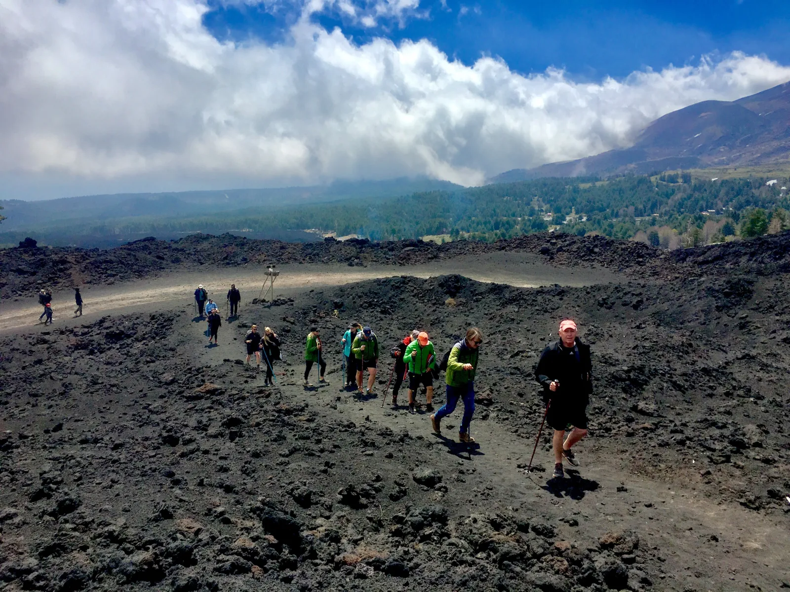 A line of walkers crossing an old lava flow high on the mountain